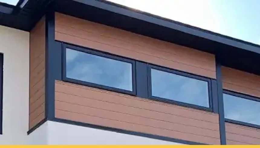 Close-up of a modern house exterior with brown horizontal cladding, black window frames, and a white wall.
