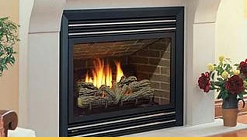 A fireplace with a glass front showing a fire burning inside, surrounded by a white mantle and decorated with potted flowers.