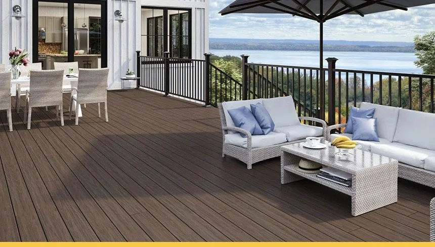 Deck with lounge chairs, a small round table, and a view of a beach with umbrellas in the distance.