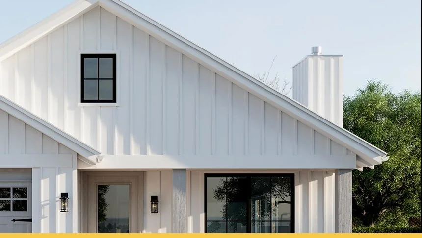 Close-up of a modern white house with a steeply sloped roof, black window frames, and outdoor wall-mounted lights, with trees in the background.