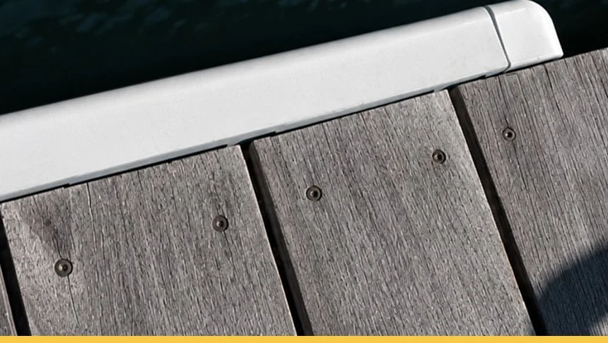 Close-up of a wooden park bench with a metal armrest and shadow.