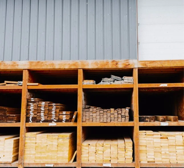 Wooden shelves stockpiled with various sizes of wooden planks and lumber in a warehouse.