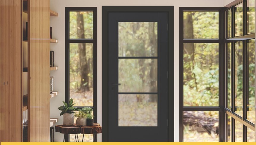 Interior view of a room with large windows showing a wooded outdoor scene, and a black door with window panes in the center, flanked by glass panels and a wooden bookshelf on the left.