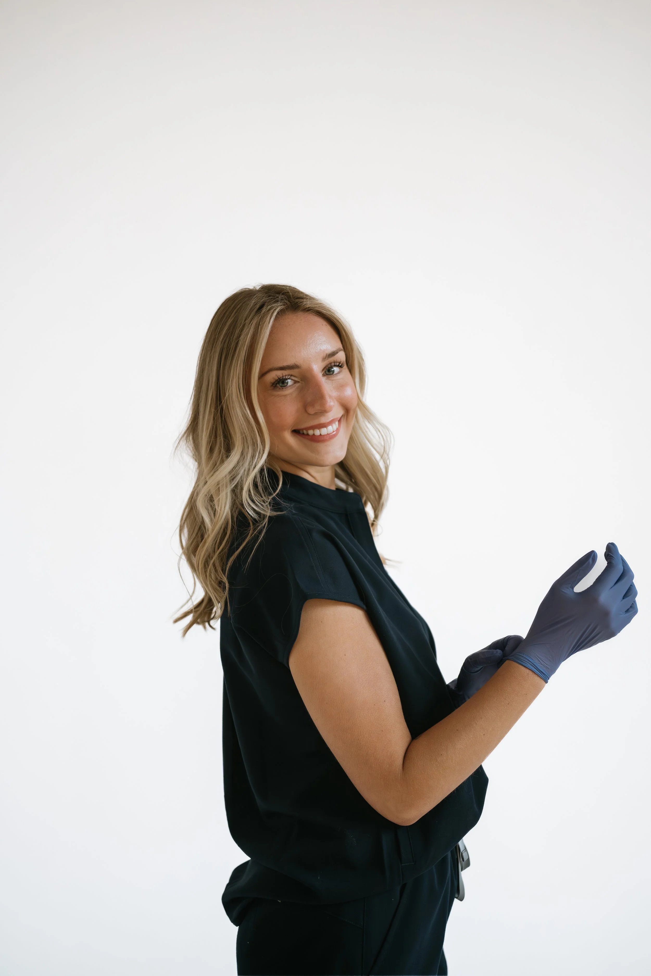 Sea Me Wellness nurse in navy scrubs and gloves holding a syringe.