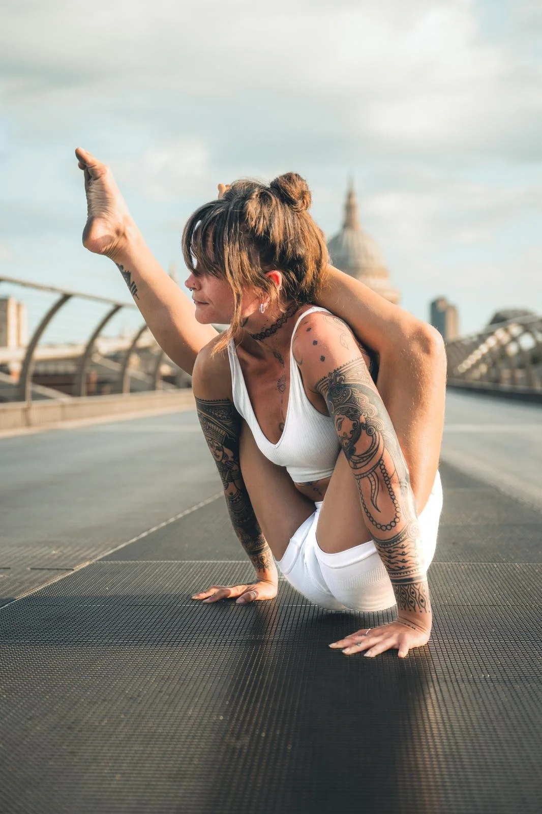 Tattooed woman practicing yoga outdoors on a rooftop with the U.S. Capitol in the background.