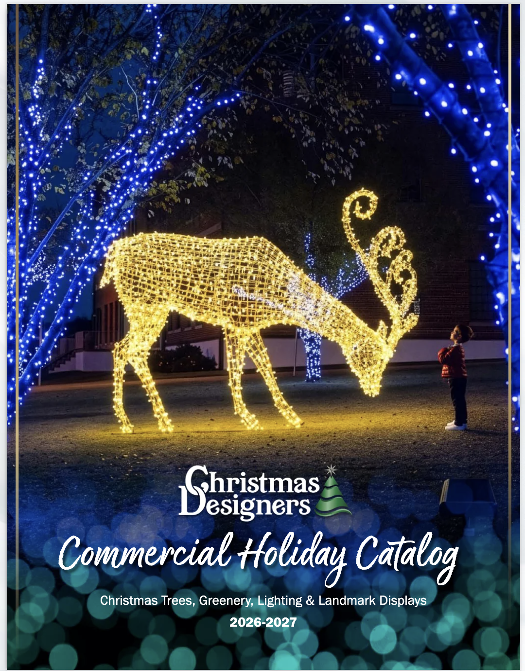 A person standing in front of a large, yellow, illuminated reindeer display surrounded by blue Christmas lights on trees at night.
