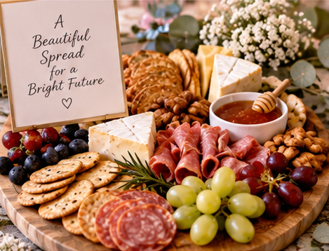 A wooden charcuterie board with various cheeses, crackers, grapes, meats, nuts, and a honey dipper, surrounded by flowers and a sign that reads 'A Beautiful Spread for a Bright Future'.