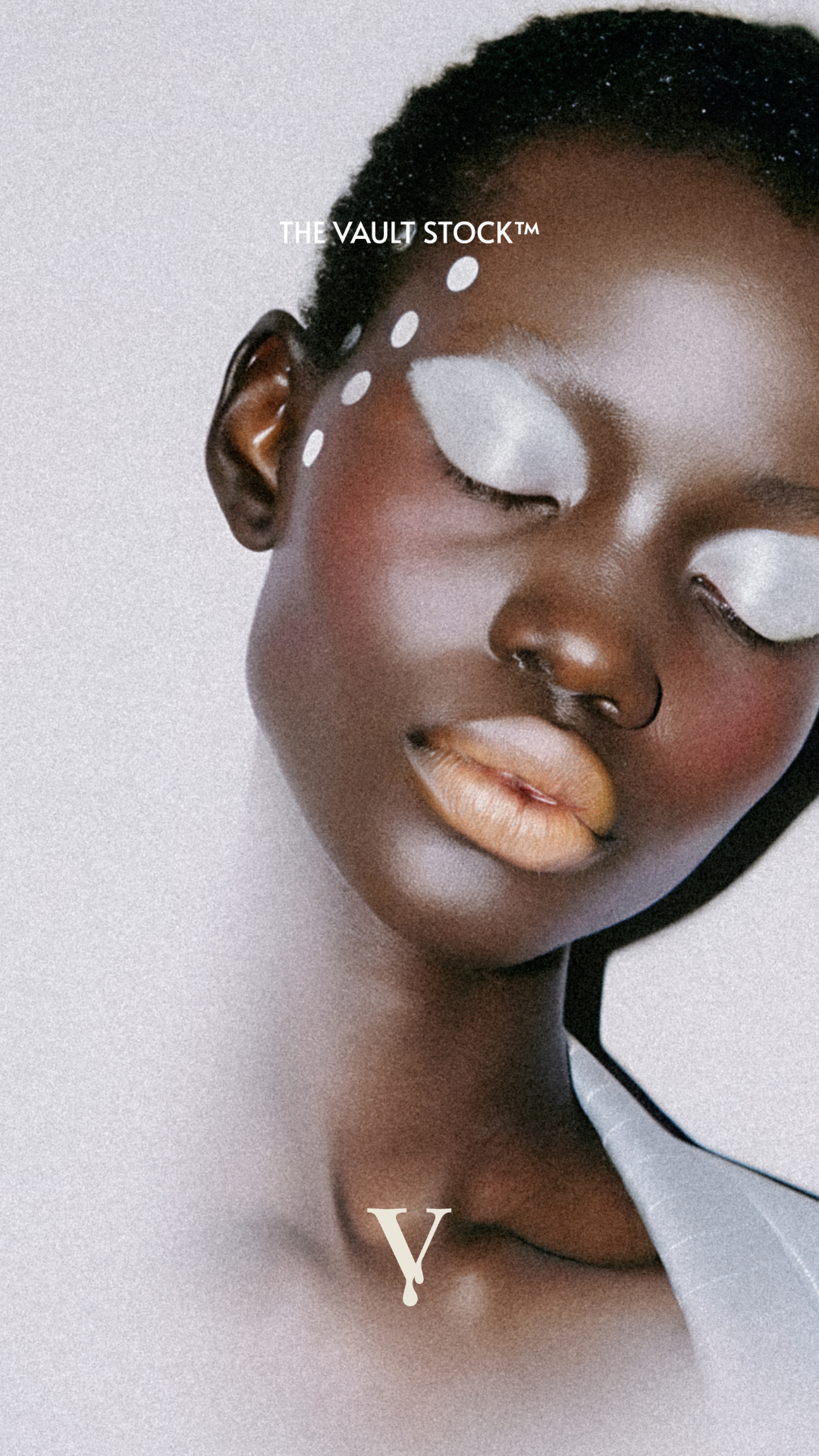 Close-up of a woman with dark skin, short curly hair, white eye makeup, and a septum nose ring. The text "THE VAULT STOCK™" is overlaid on her forehead, and the letter "Y" is near her collarbone.