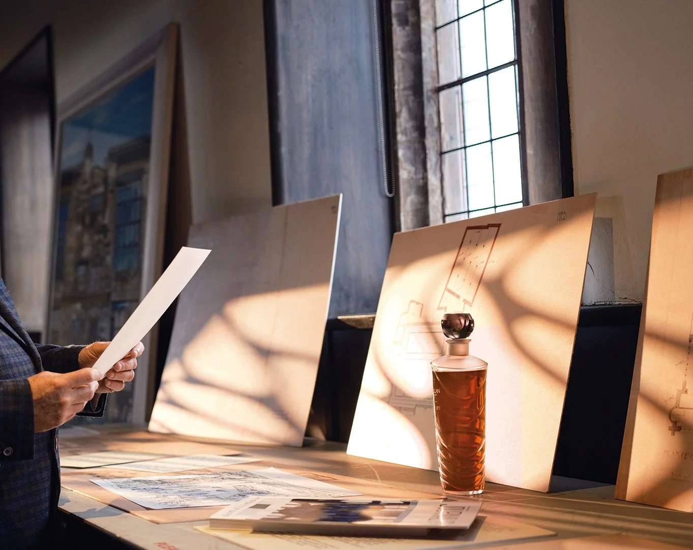 Luxury whisky bottle next to archival drawings of Charles Rennie Mackintosh's work
