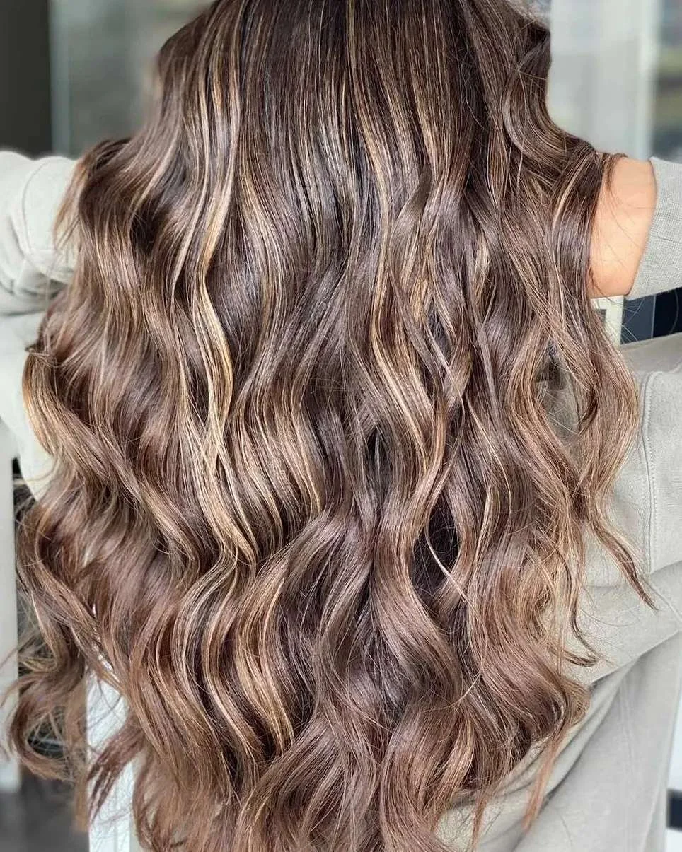 Woman with long, wavy, light brown hair with blonde highlights.