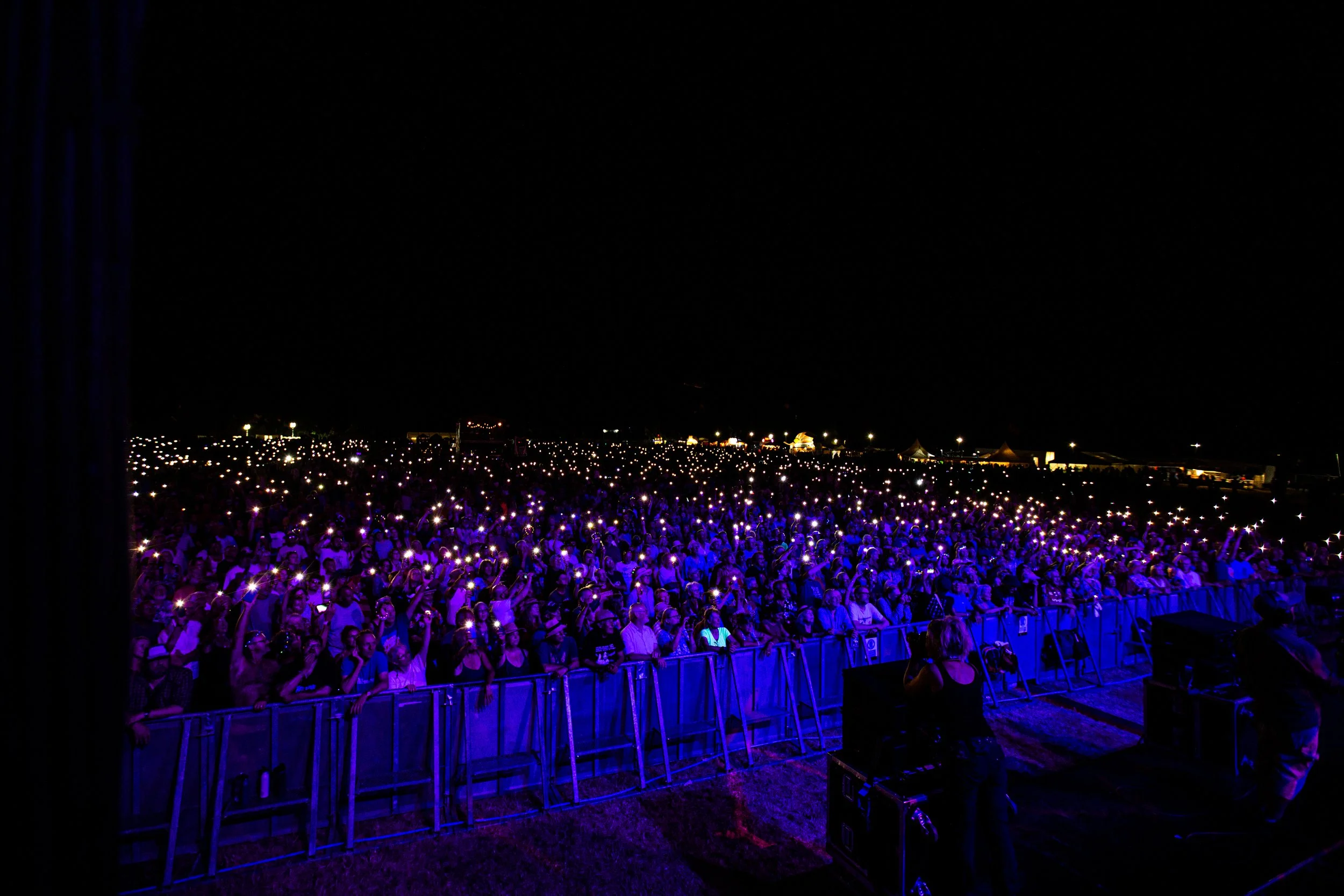 A large crowd at night illuminated by many small lights, with some tents and structures in the background.