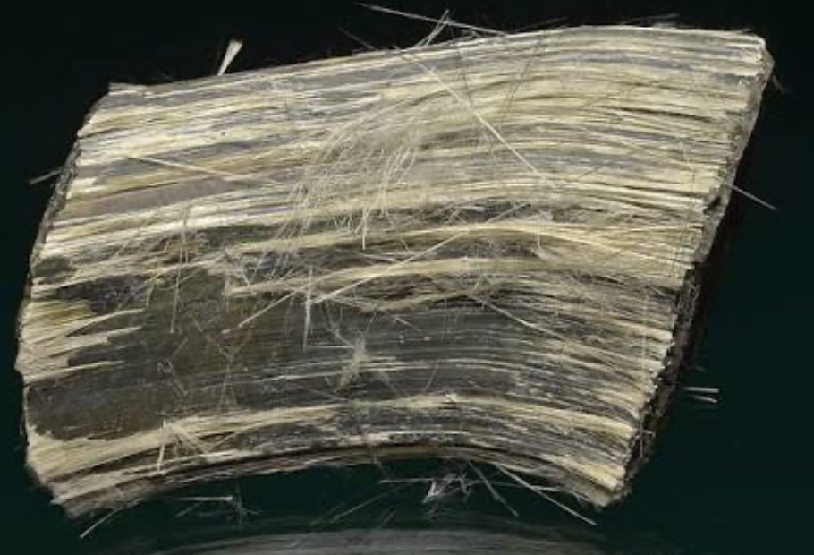 Close-up view of a rough, layered, grayish-black rock with numerous thin, white, fibrous veins running through it.