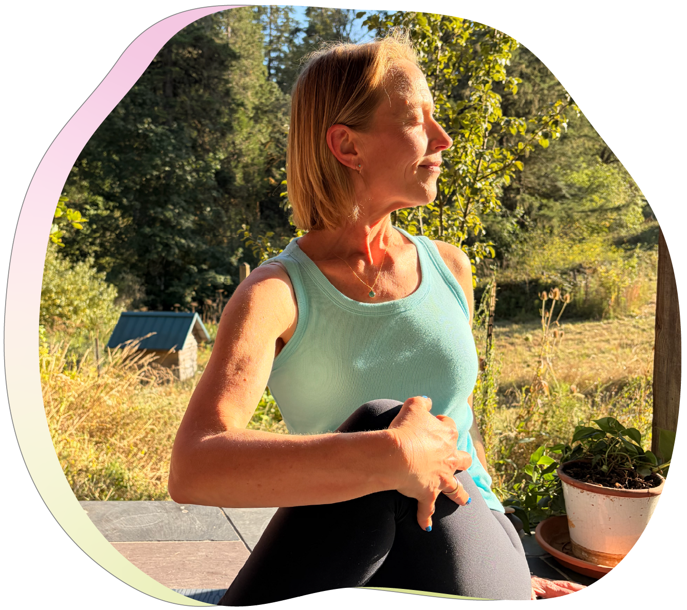 A woman practicing yoga outdoors on a sunny day, sitting on a mat with a small plant in a pot nearby, surrounded by trees and nature.