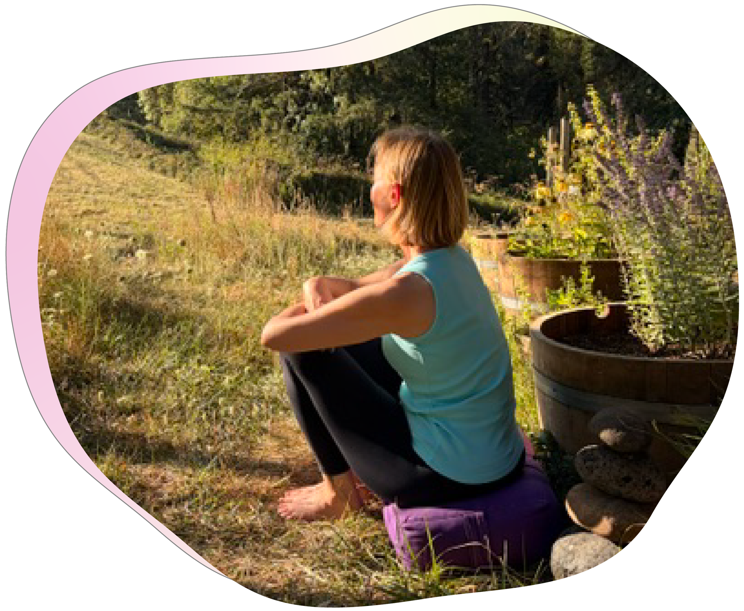 A woman sitting outdoors among plants and flowers, with a large plant in a black pot next to her, and trees and greenery in the background.