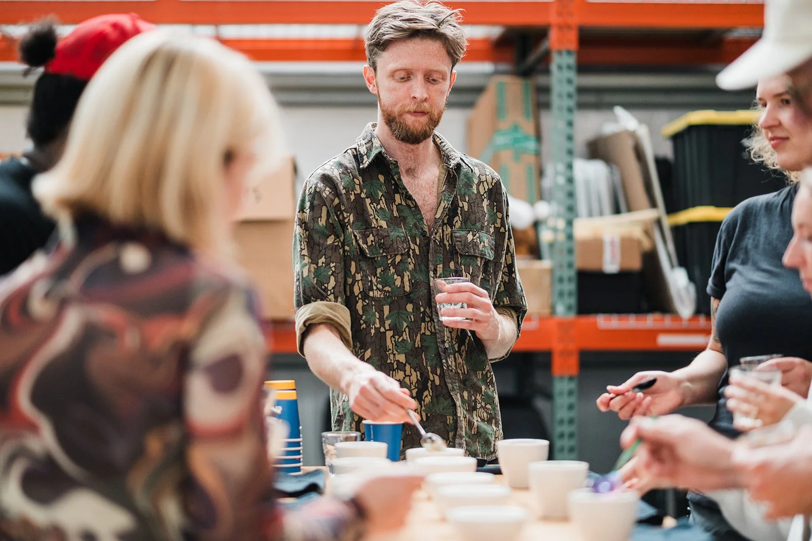 A group of people taste testing freshly roasted coffees. They have clipboards and spoons and are slurping away. This is called a coffee cupping.