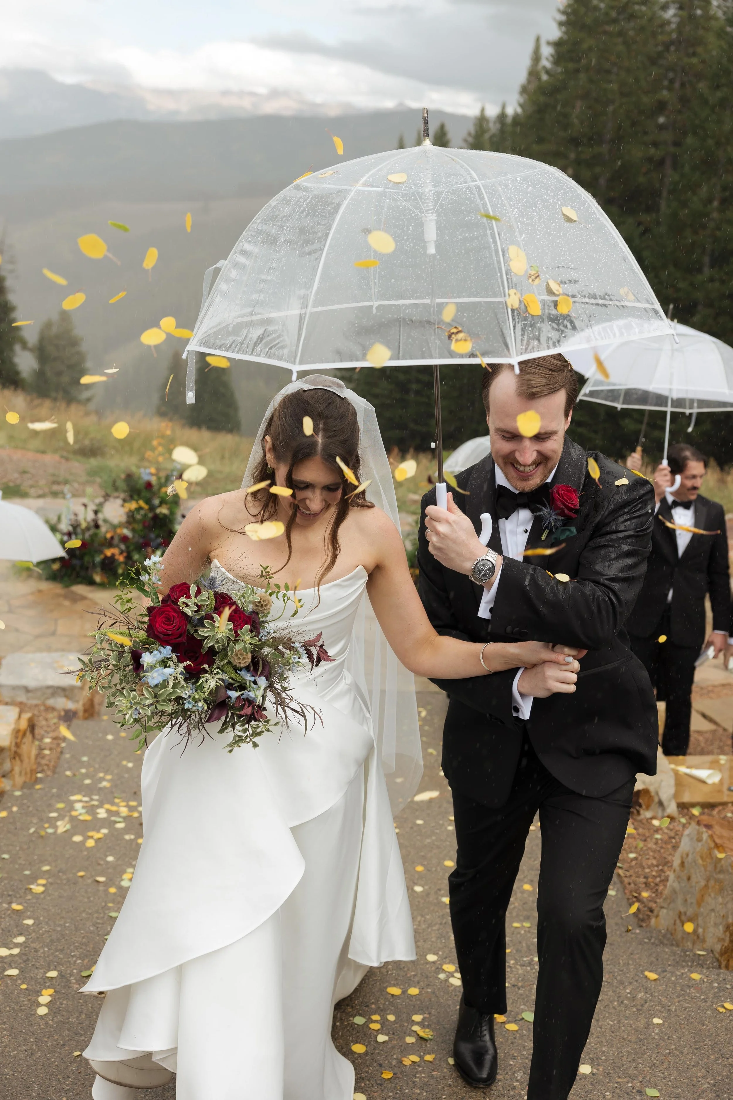 a groom protecting his bride from the rain at their luxury wedding in vail colorado
