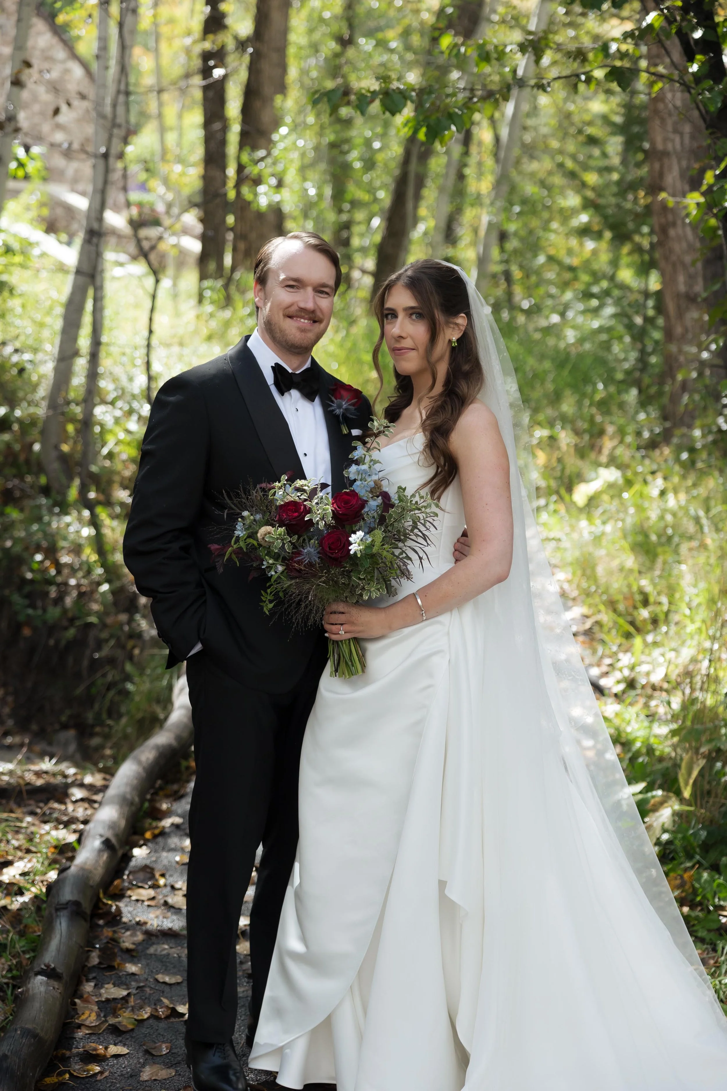 a newlywed couple posing with flowers in a forest in beaver creek colorado