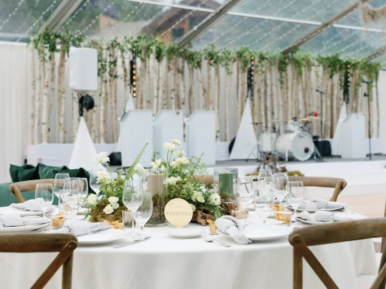Elegant wedding table setting with floral centerpiece, candles, and birch backdrop for elevated wedding design ideas.