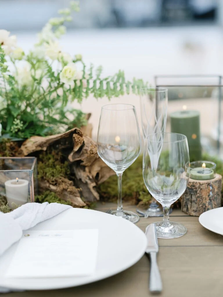 Elegant place setting with glassware, moss, and candles showcasing natural-inspired wedding design ideas.