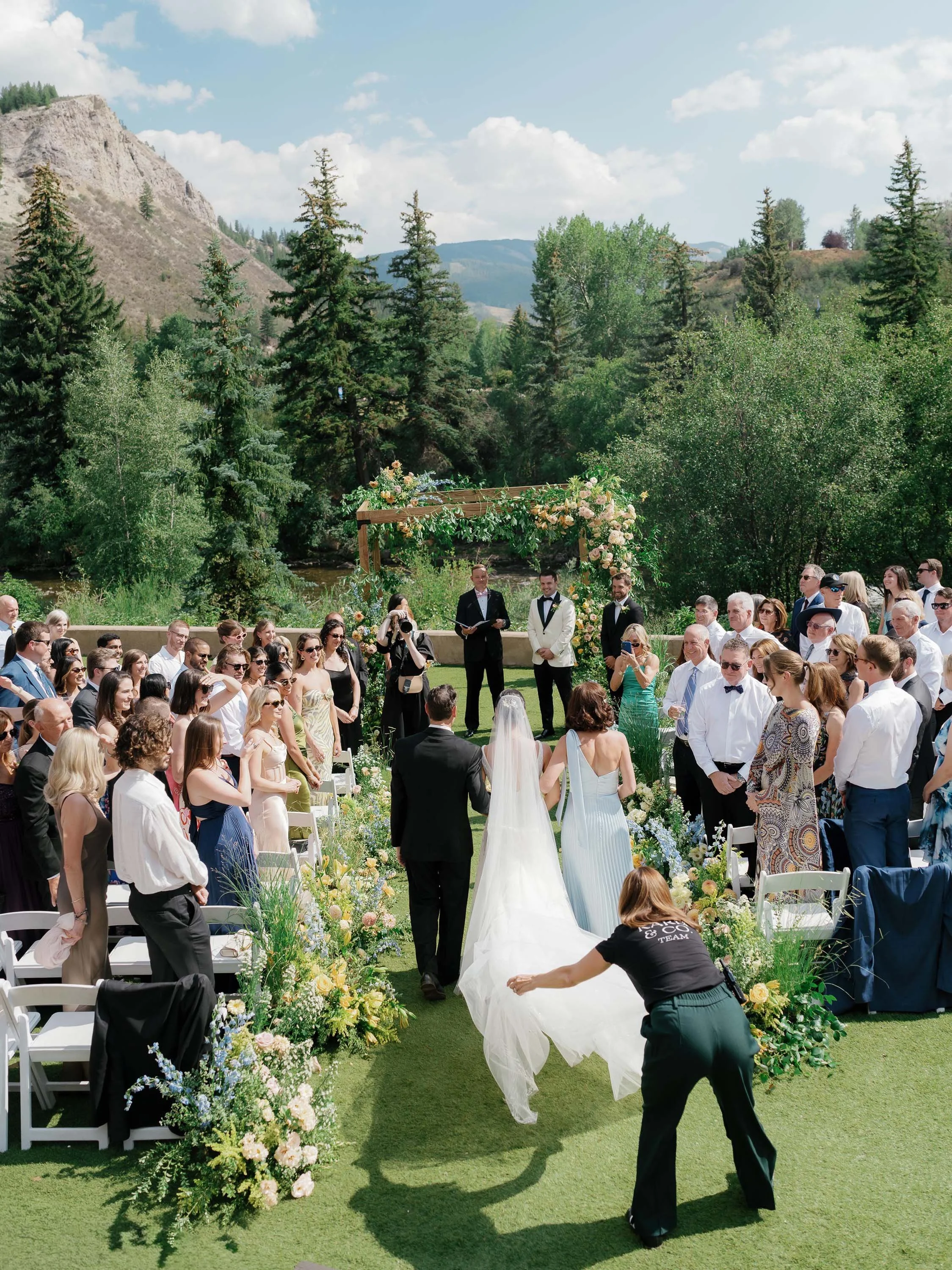 a bride and parents walking down the aisle to the groom