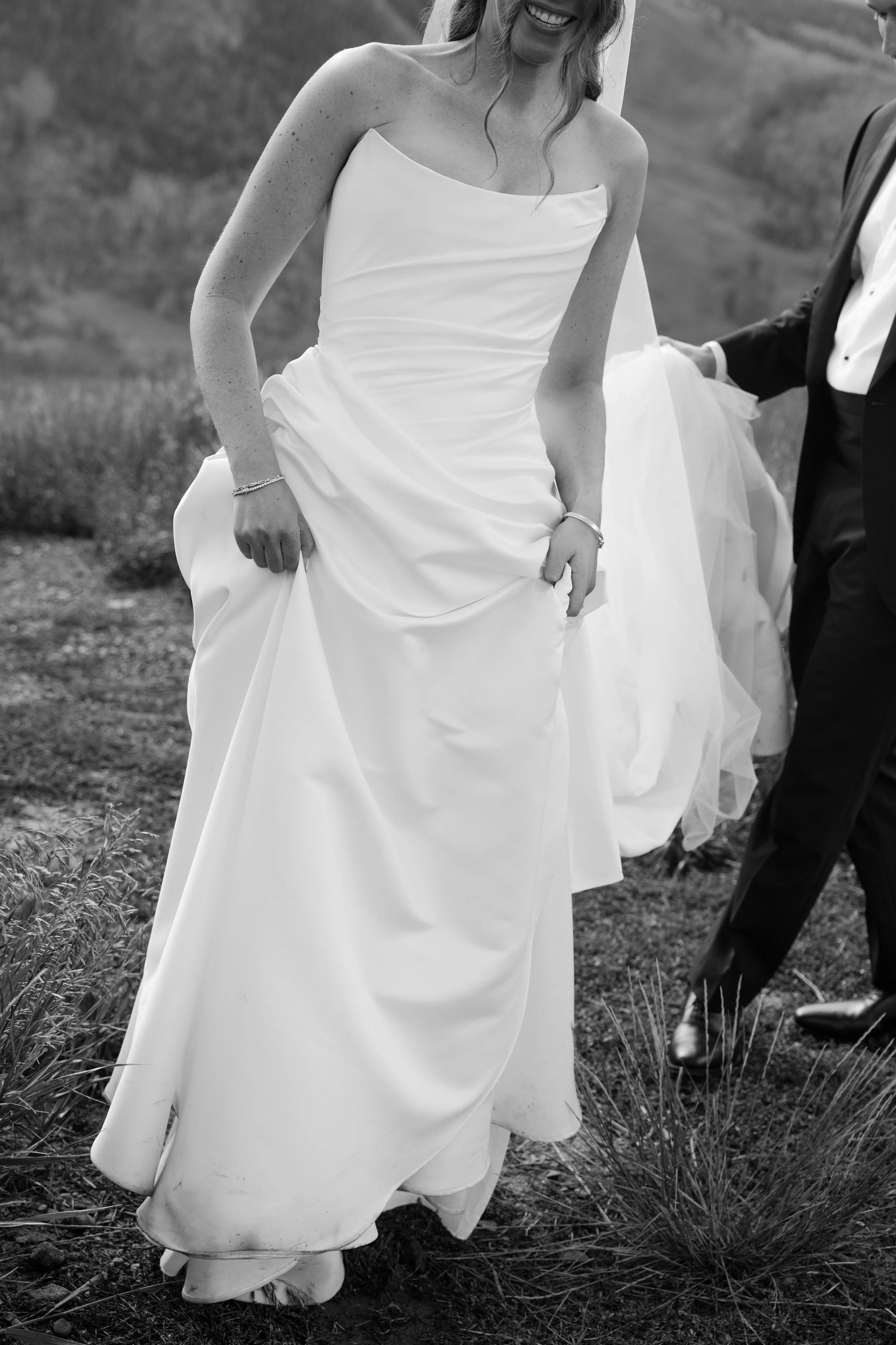 a beautiful bride holding her dress as she walks in a meadow in colorado
