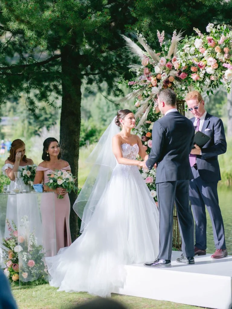 bride and groom standing under a floral arch saying their vows while planning a destination wedding in New England