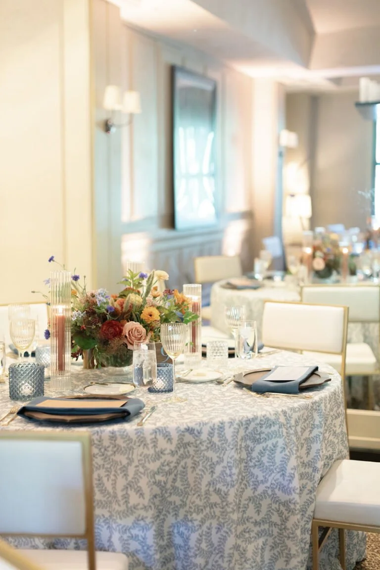 Elegant reception table showcasing thoughtful wedding planner design with florals, blue glassware, and layered textures.