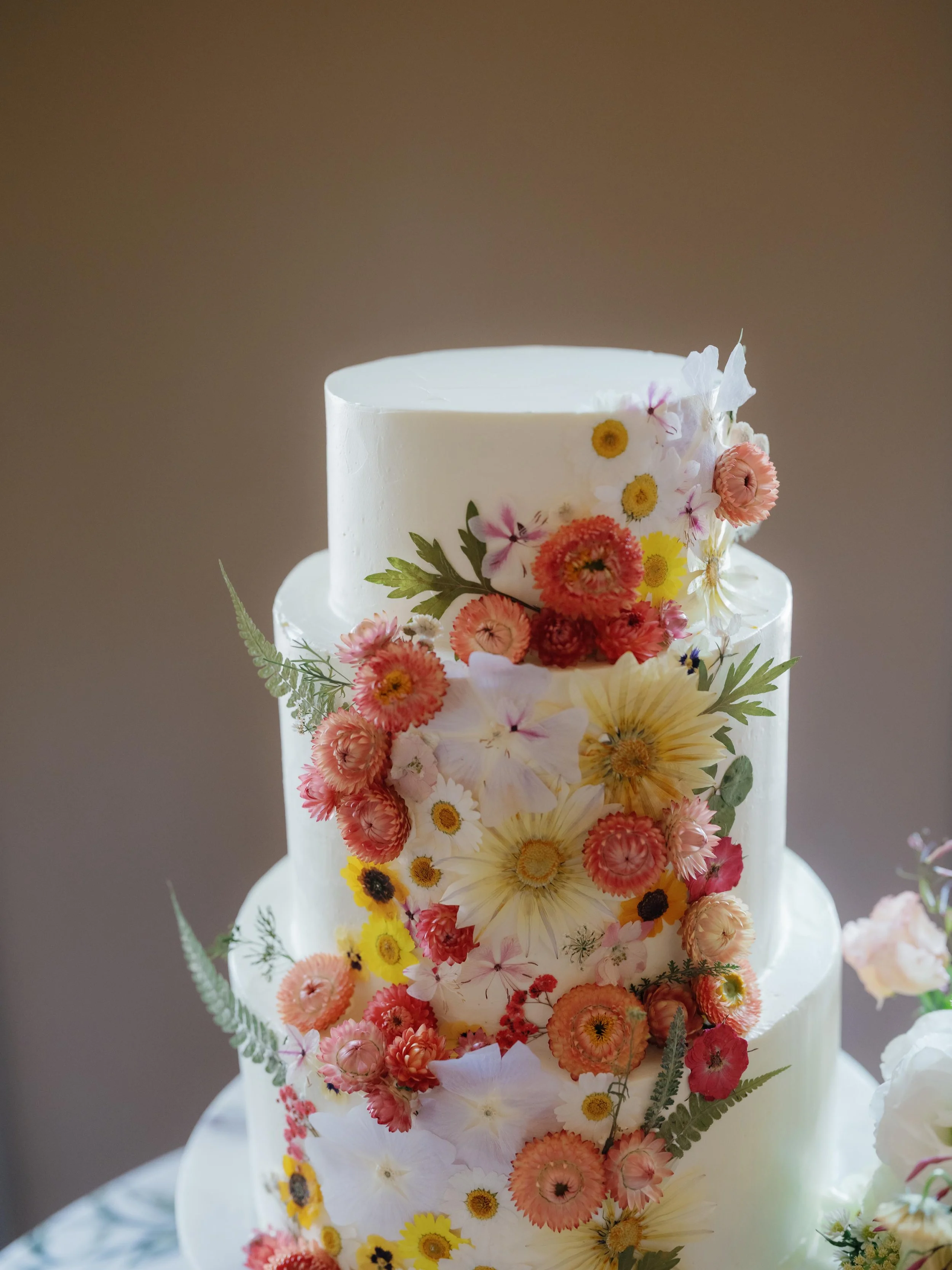 a three tiered wedding cake with edible flowers on it