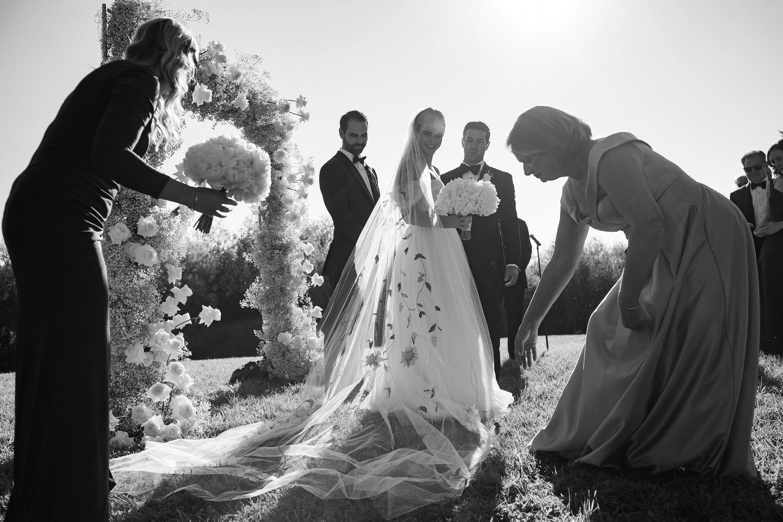 a bridal party helping the bride with her dress outside on a sunny day in aspen colorado