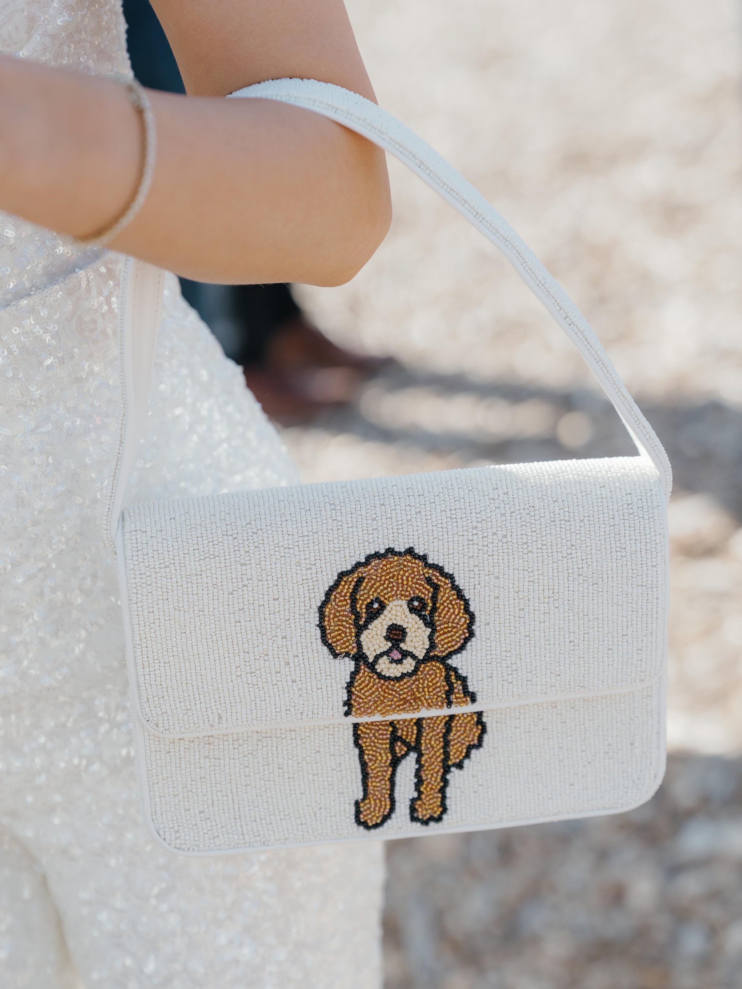 a beaded white purse with a cute dog on it worn by the bride