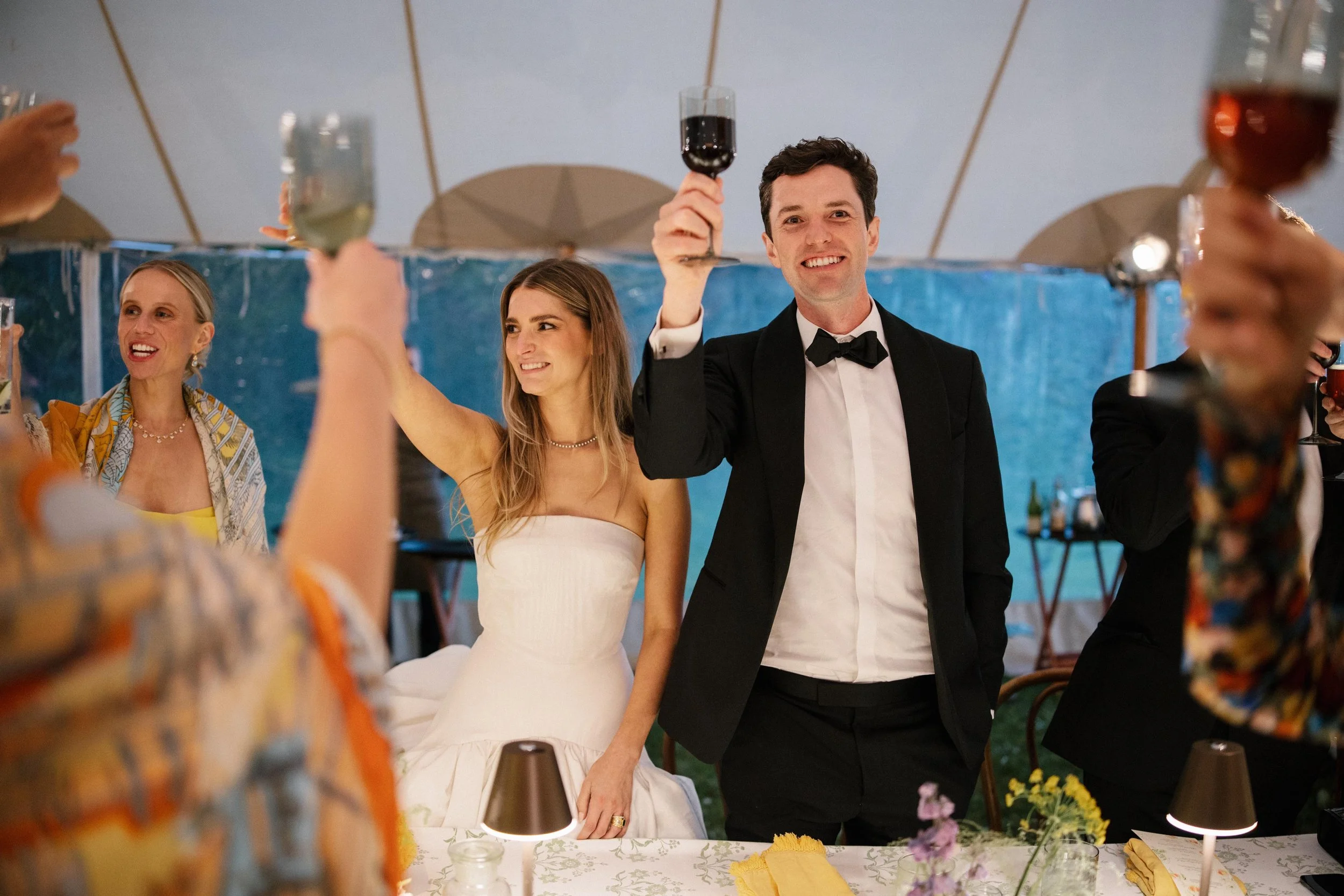a bride and groom lifting up their glasses to cheers at their rehearsal dinner