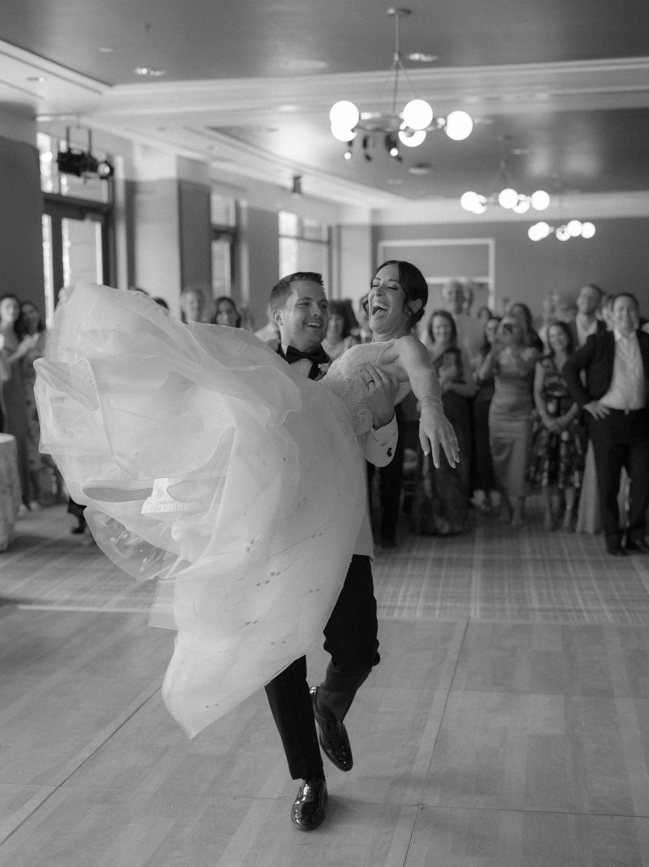 a happy newlywed groom lifting up his bride on the dance floor