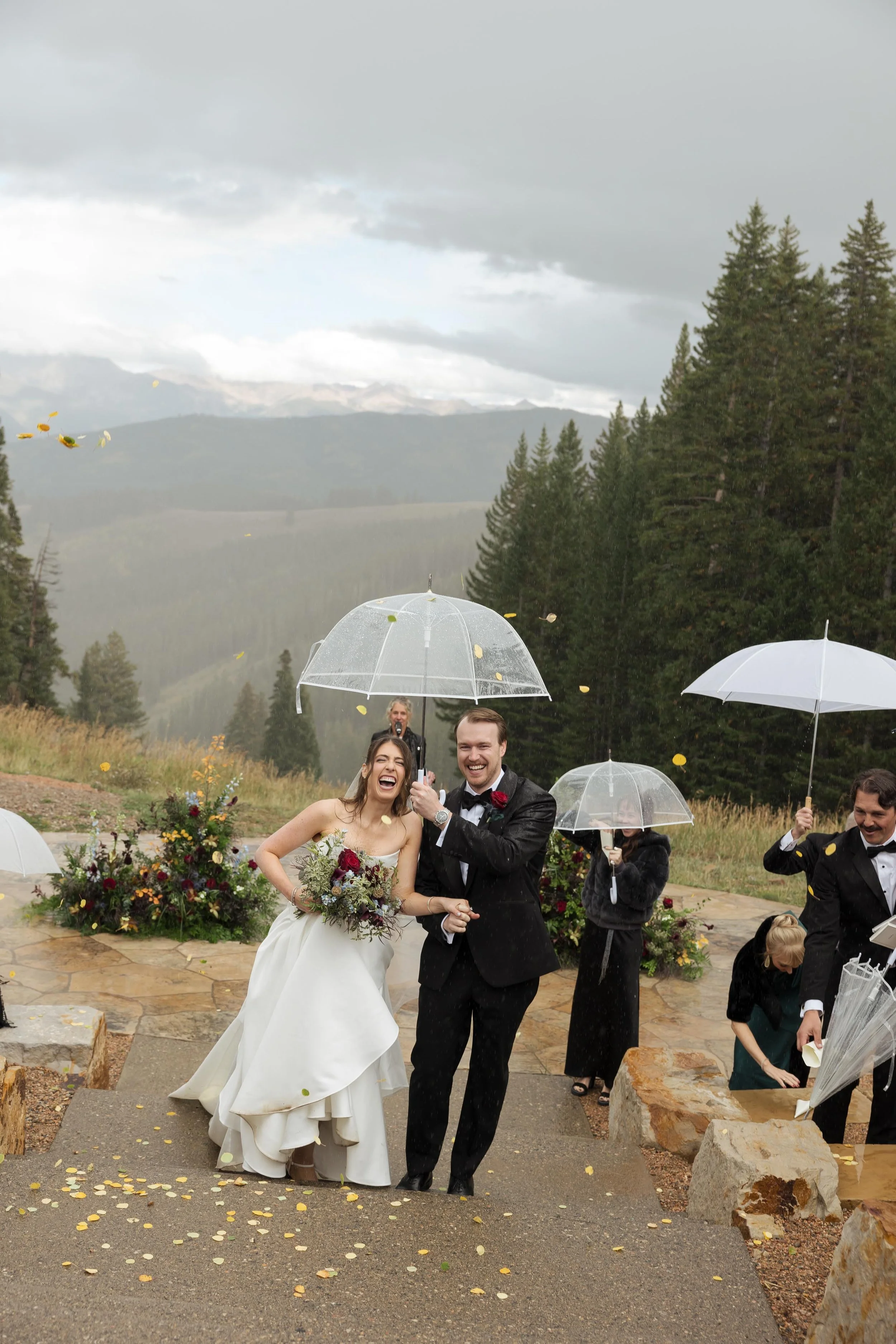 a groom holding an umbrella for his bride while it rains in colorado