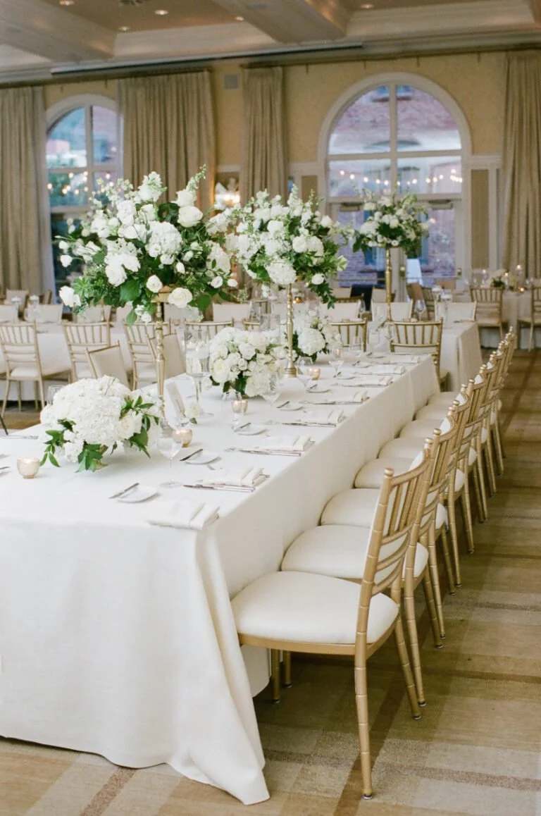 Classic wedding planner design with tall white floral centerpieces, gold chairs, and elegant ivory linens.