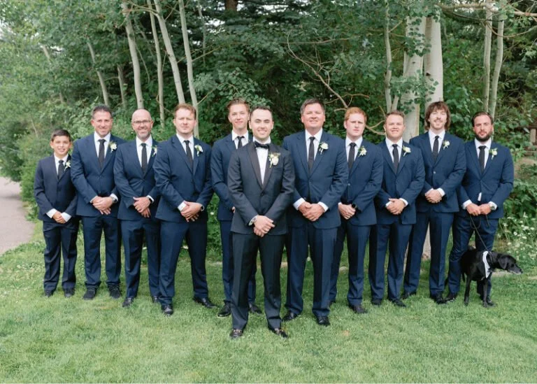 Groom with groomsmen in navy suits and boutonnieres, showcasing classic and cohesive wedding design ideas.
