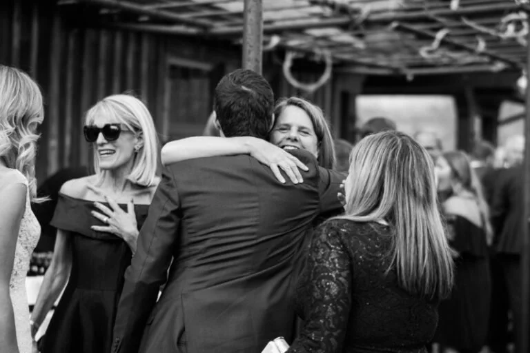 Wedding guests embrace and connect during cocktail hour, capturing the heart of the guest experience.