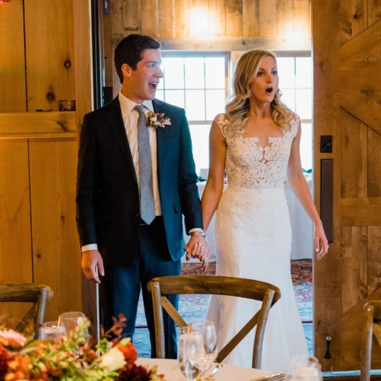 Bride and groom reacting with joy as they enter their warmly decorated wedding reception space.