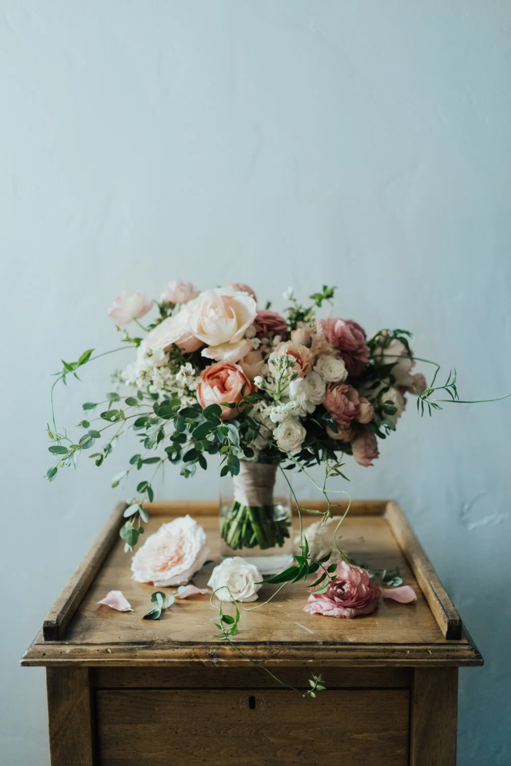 Romantic bridal bouquet with soft pink and white flowers arranged on a vintage wooden table.