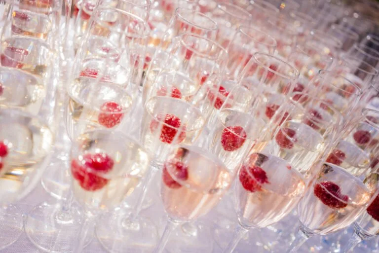 Champagne flutes with raspberries ready for guests.