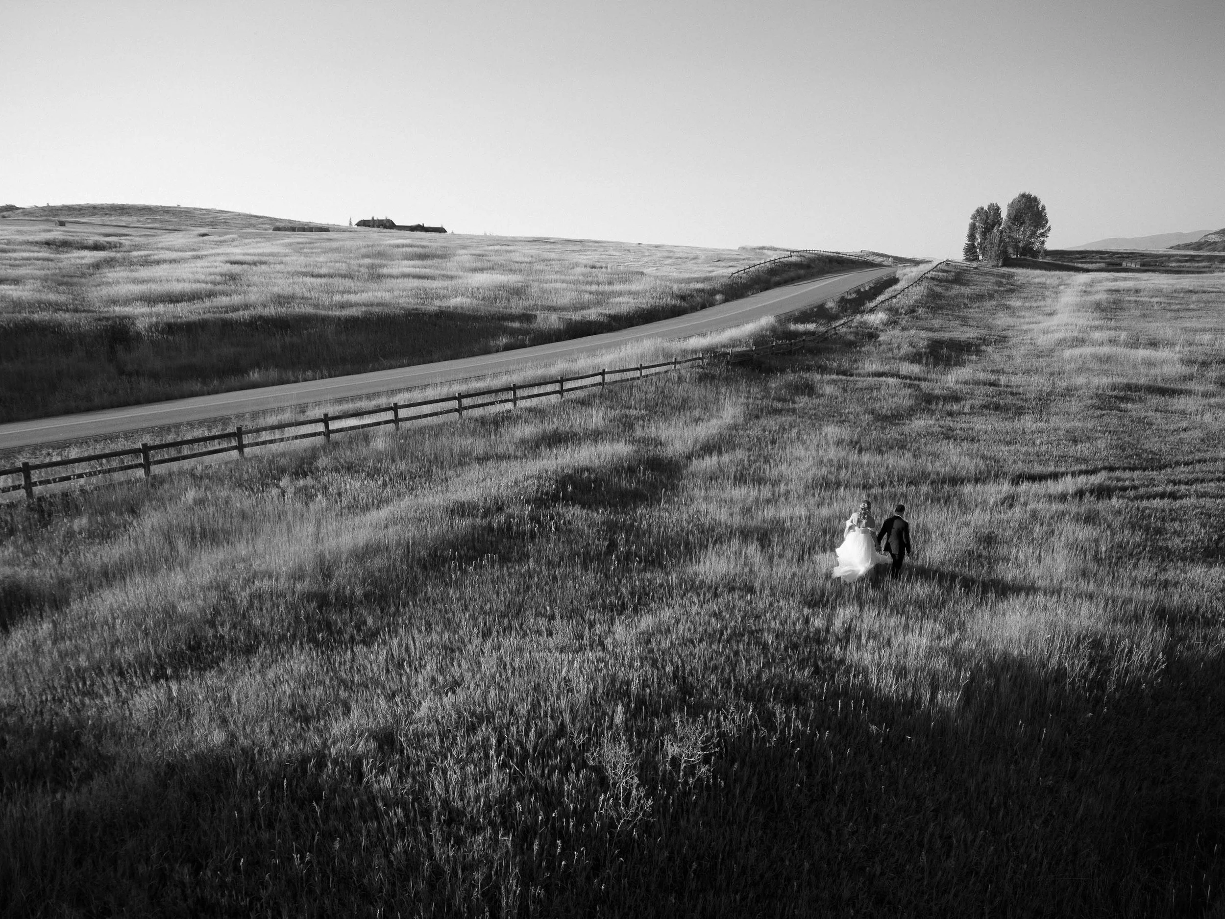 bride and groom walking through a big field on their wedding day in colorado