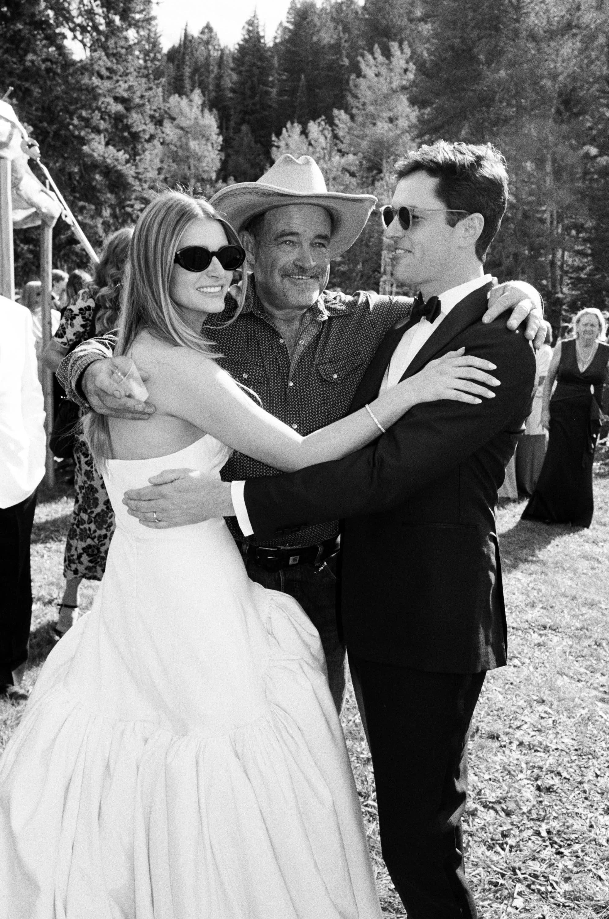 bride and groom embracing a family member before their luxurious colorado wedding