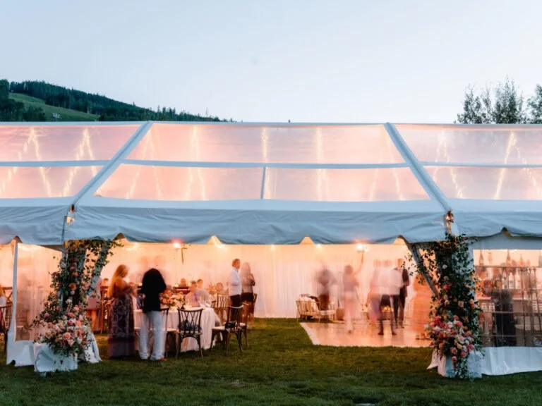 Evening tented reception glowing with lights and florals during mountain multi-day wedding experiences.