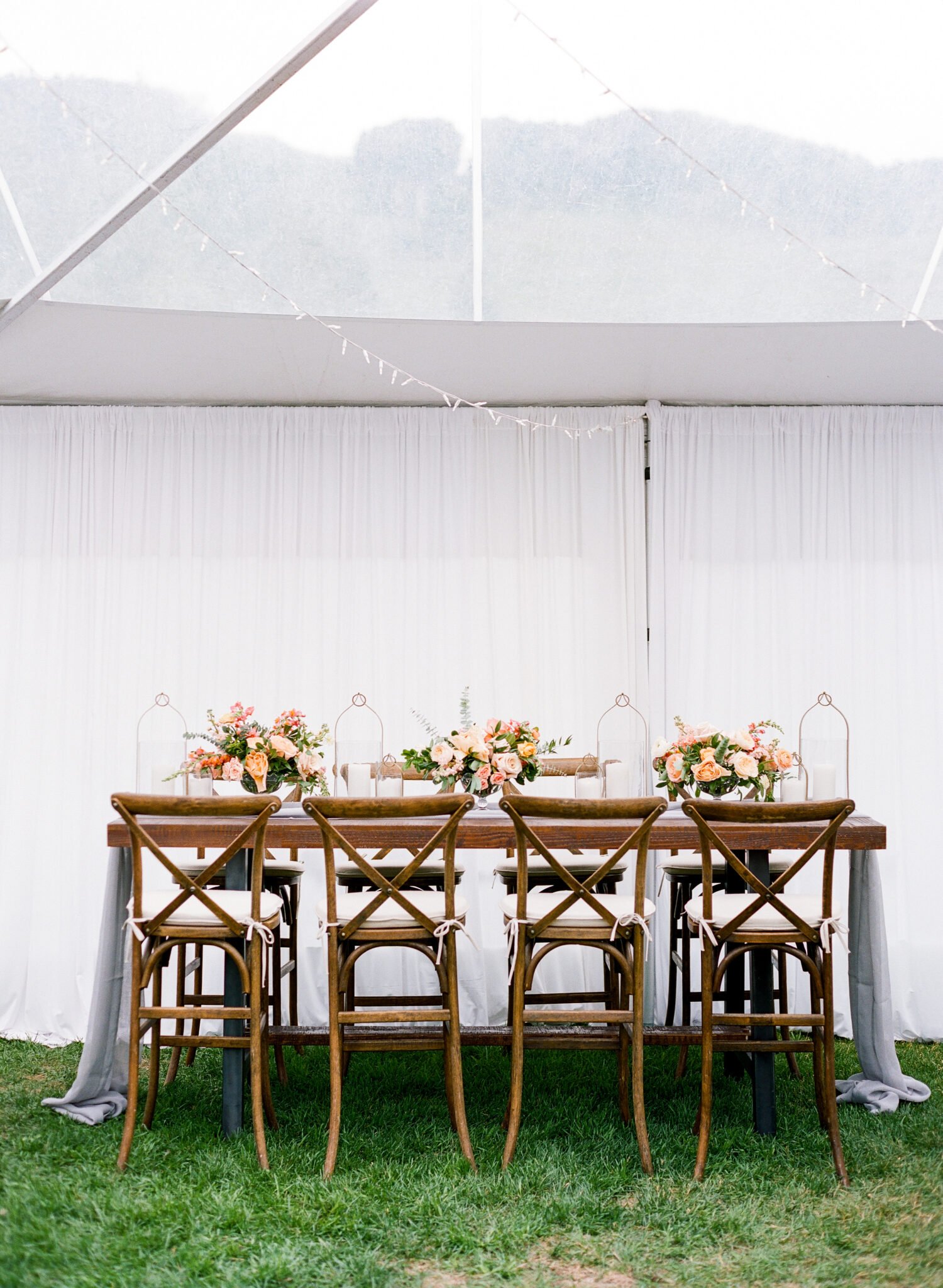 Chic wedding table with wooden chairs and floral centerpieces.