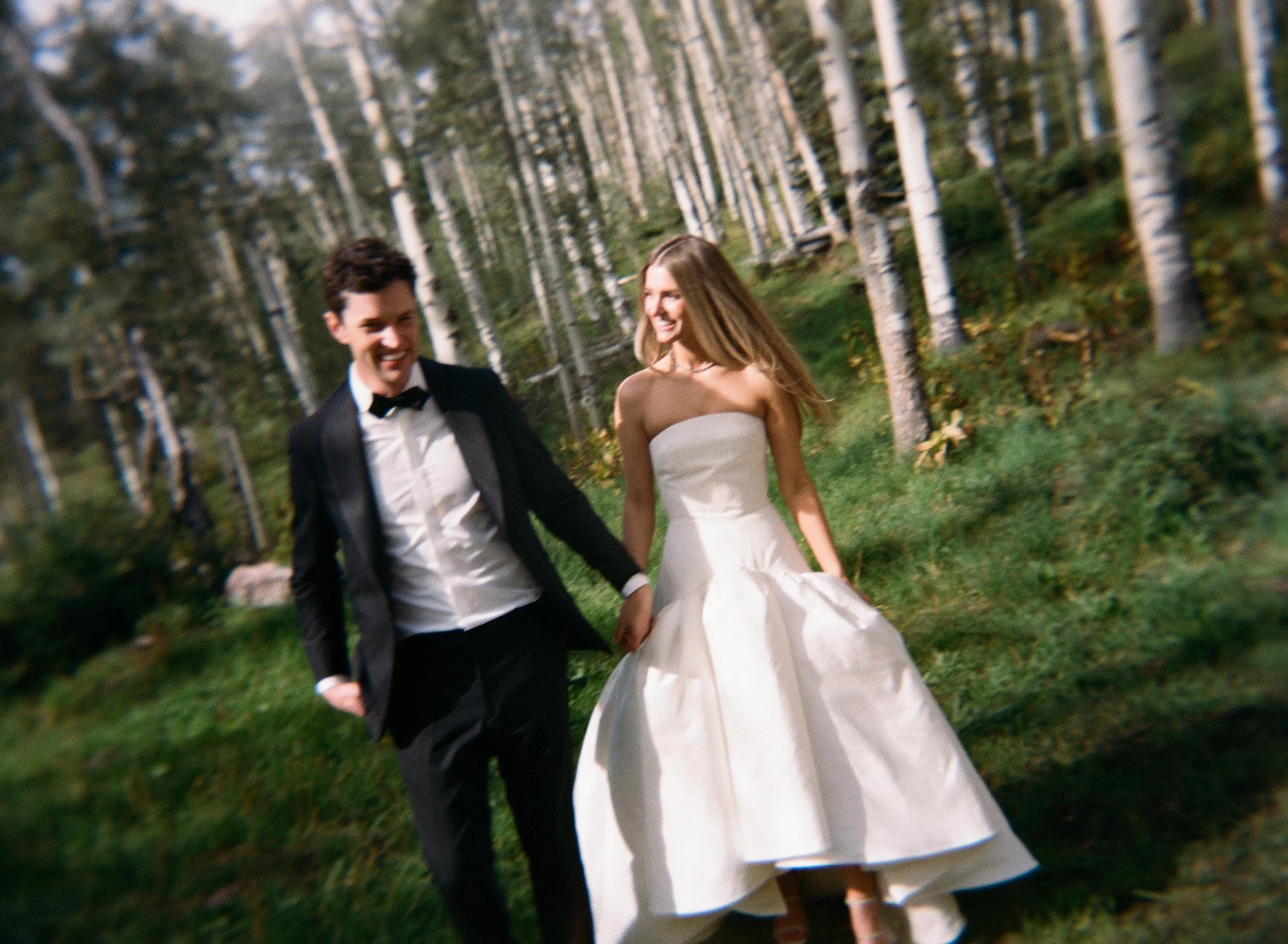 a bride and grooms walking happily through the colorado mountain woods next to their wedding ceremony venue