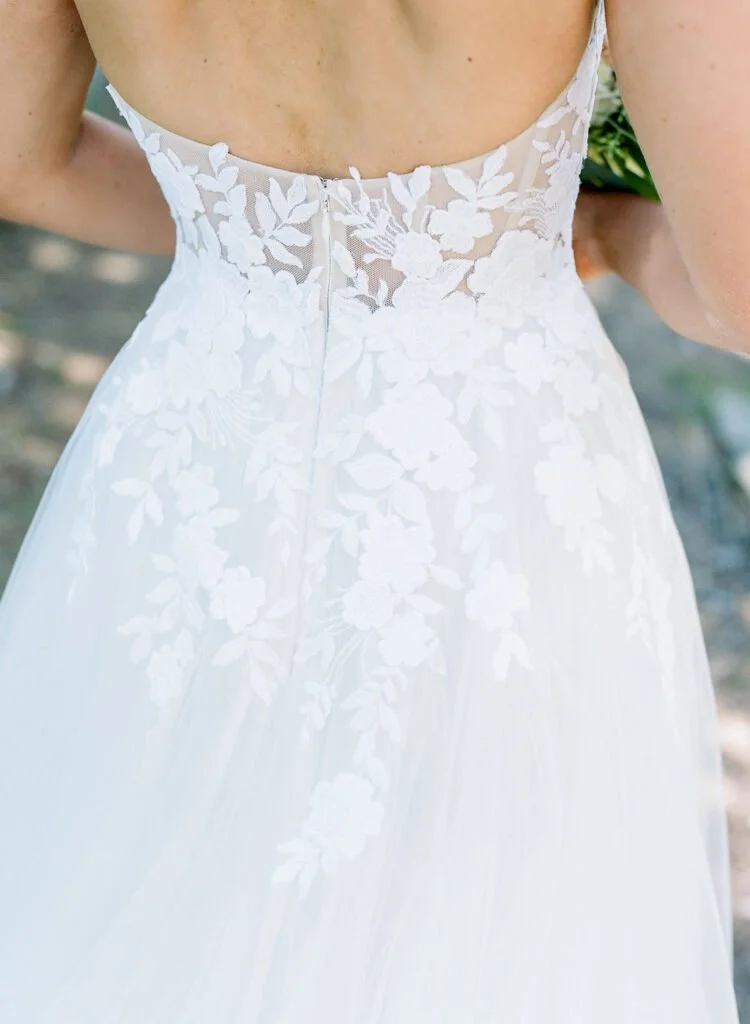 Close-up of a bride’s lace wedding gown featuring delicate floral appliqué and sheer detailing on the back, captured during a wedding at The Cliff House.