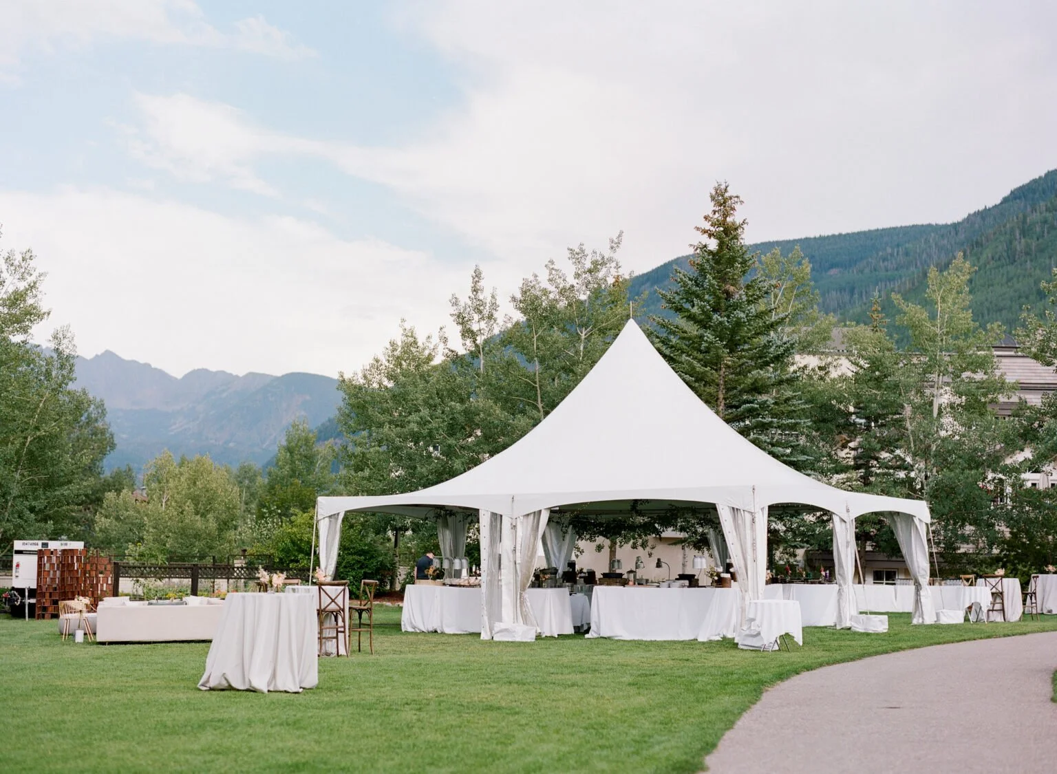 Elegant white tented wedding setup nestled in scenic mountain landscape.