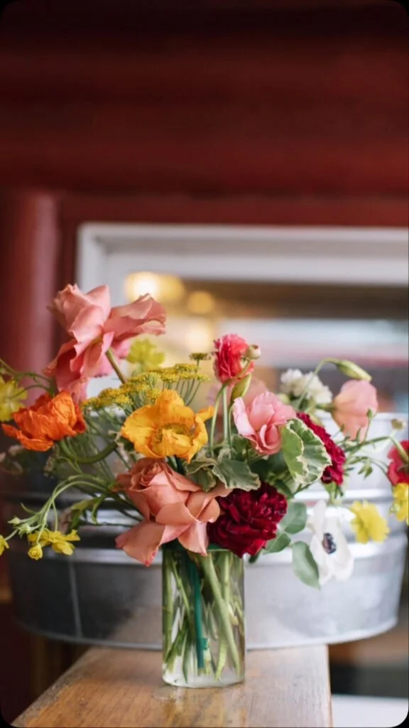 Spring wedding color palettes with bold florals in coral, yellow, and red arranged in a vibrant centerpiece