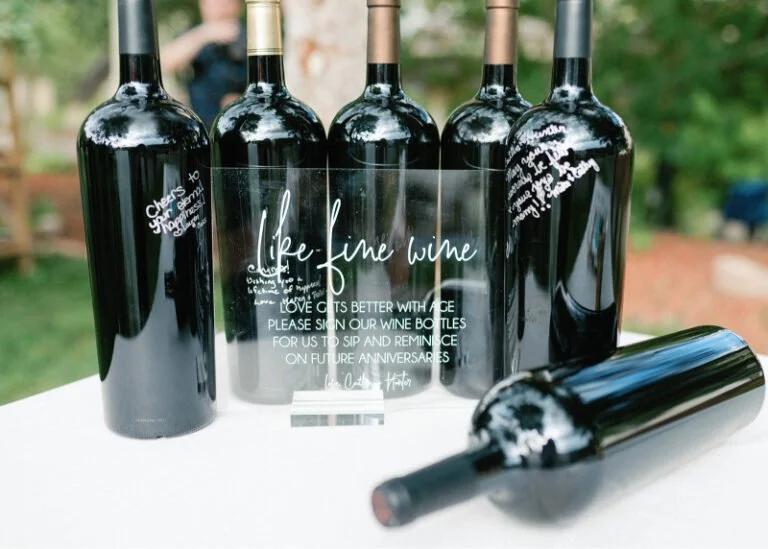 Wine bottle guest book with acrylic sign offering creative and meaningful wedding design ideas.