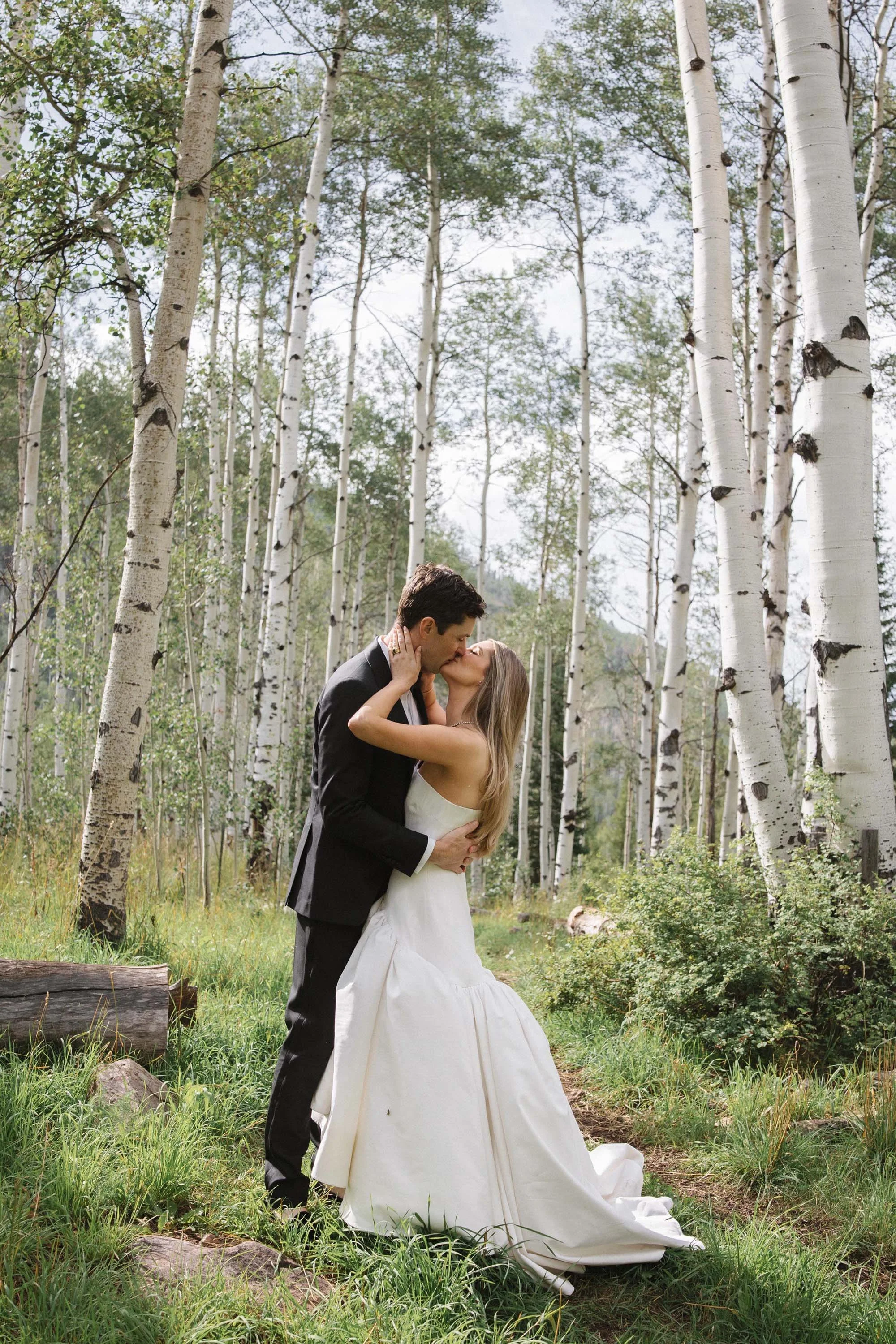 bride and groom kissing each other in a forest in vail colorado