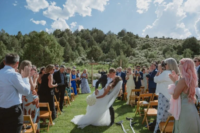 Bride and groom celebrating down the aisle during an outdoor Colorado ranch wedding at Lazy J Ranch surrounded by guests and mountain views.